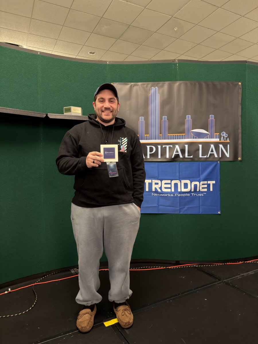 Attendee posing with badge at sponsor banners