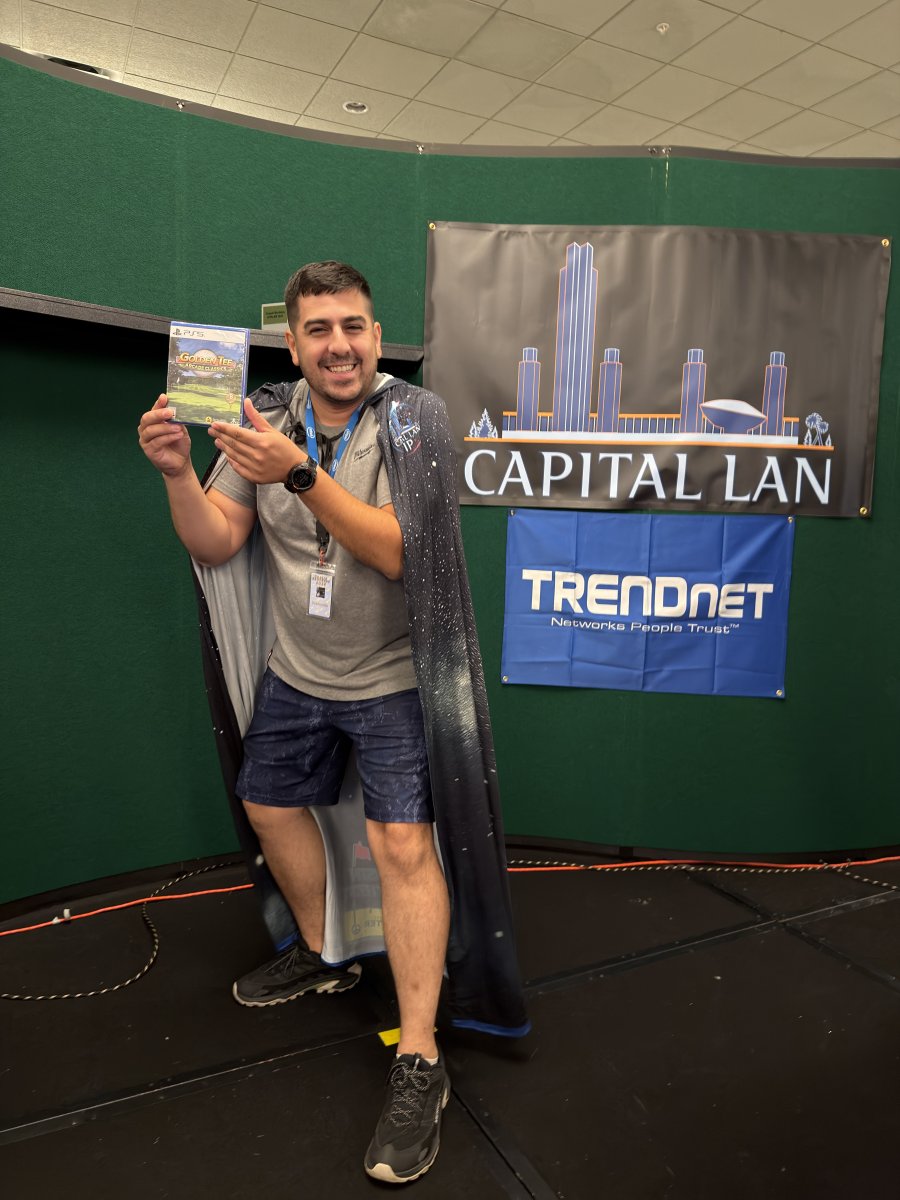 Attendee posing with game prize on stage