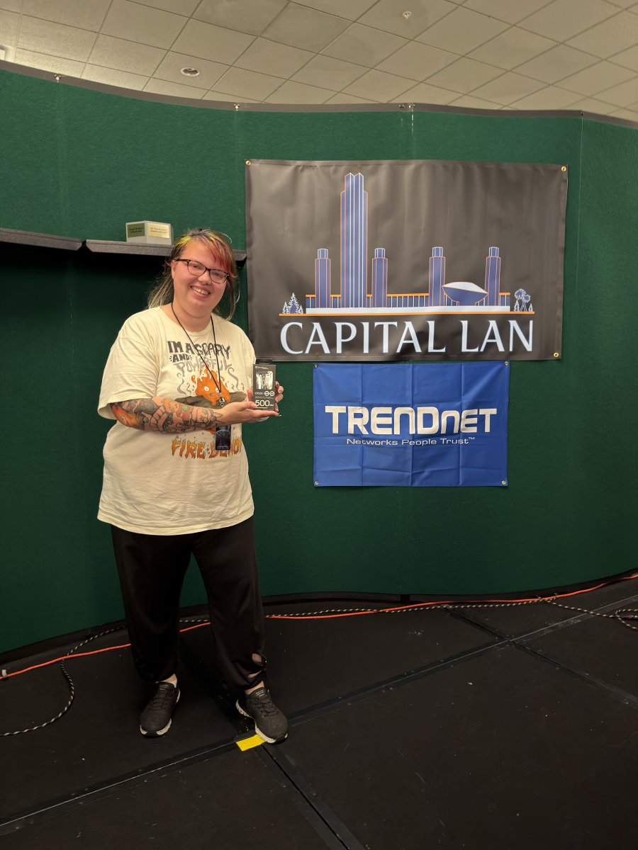 Attendee holding prize in front of Capital LAN banner