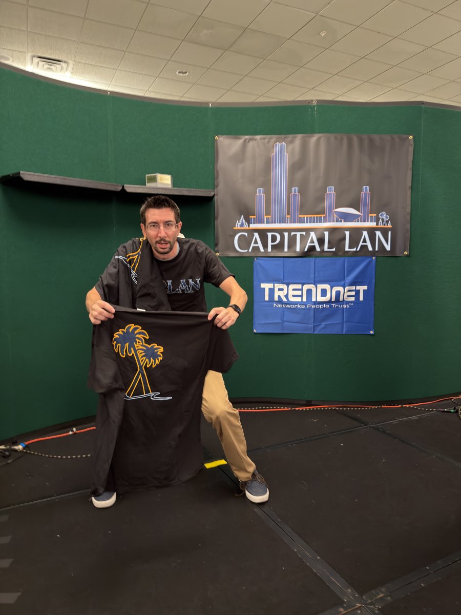 Person holding Capital LAN T-shirts on stage