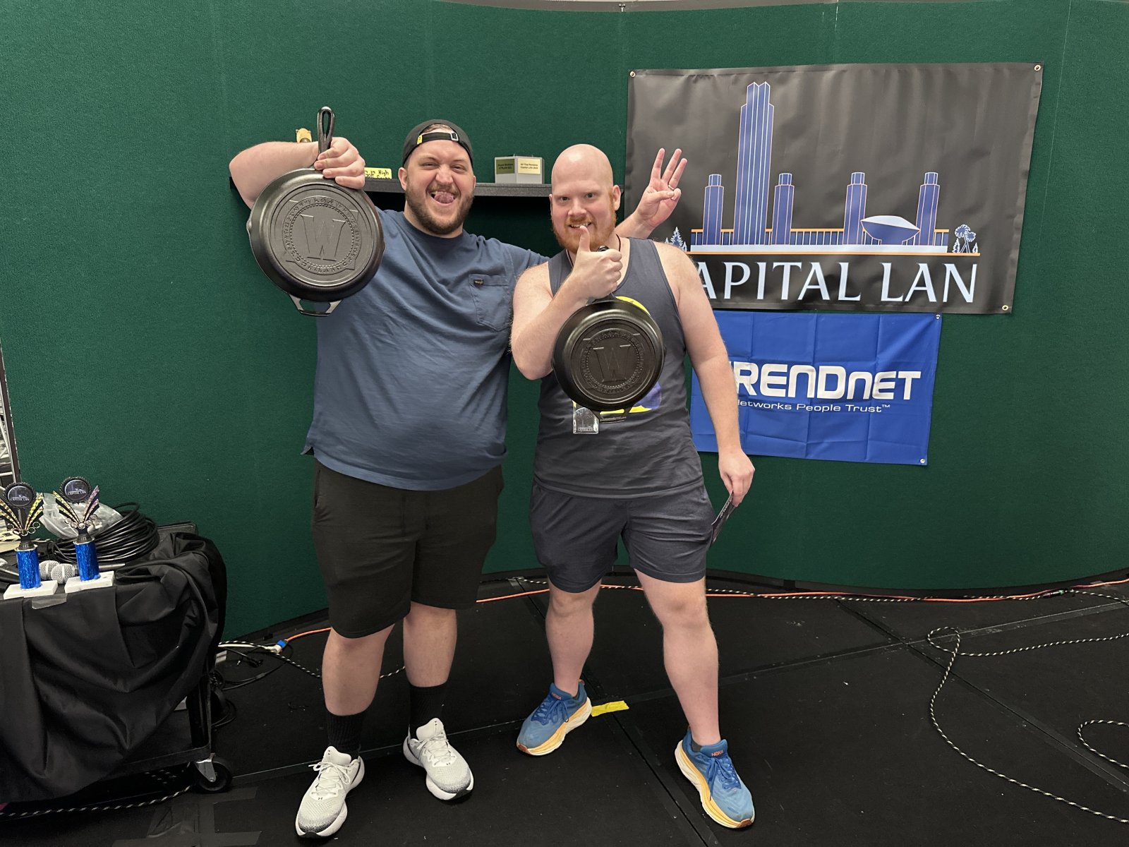 Two attendees holding frying pan prizes