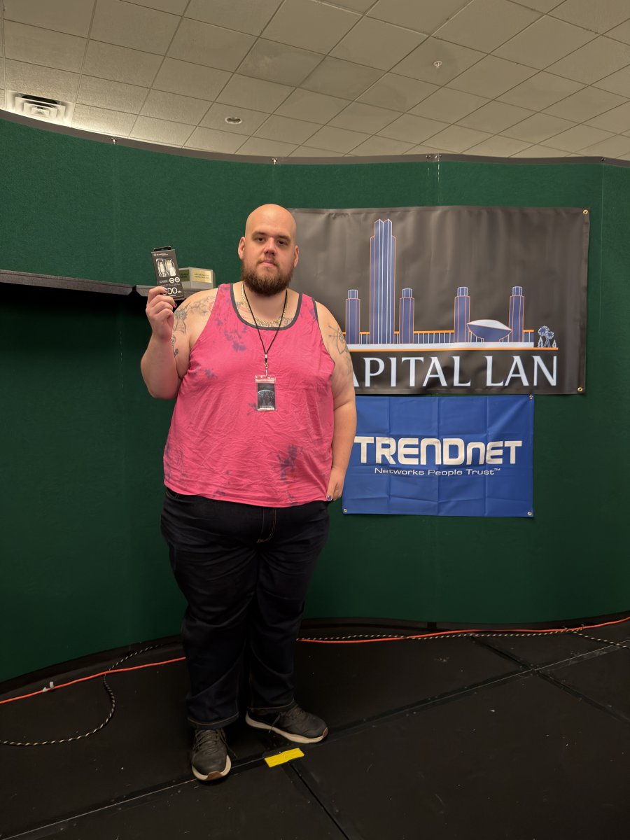 Attendee holding prize in front of Capital LAN banner