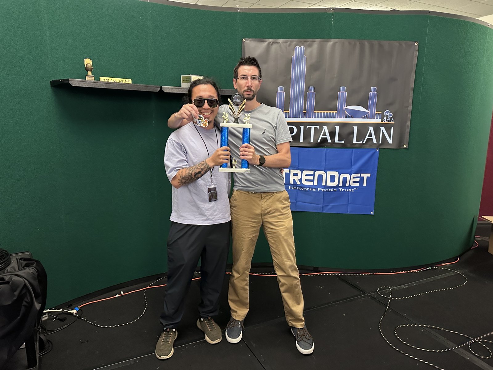 Two attendees holding a trophy and medal