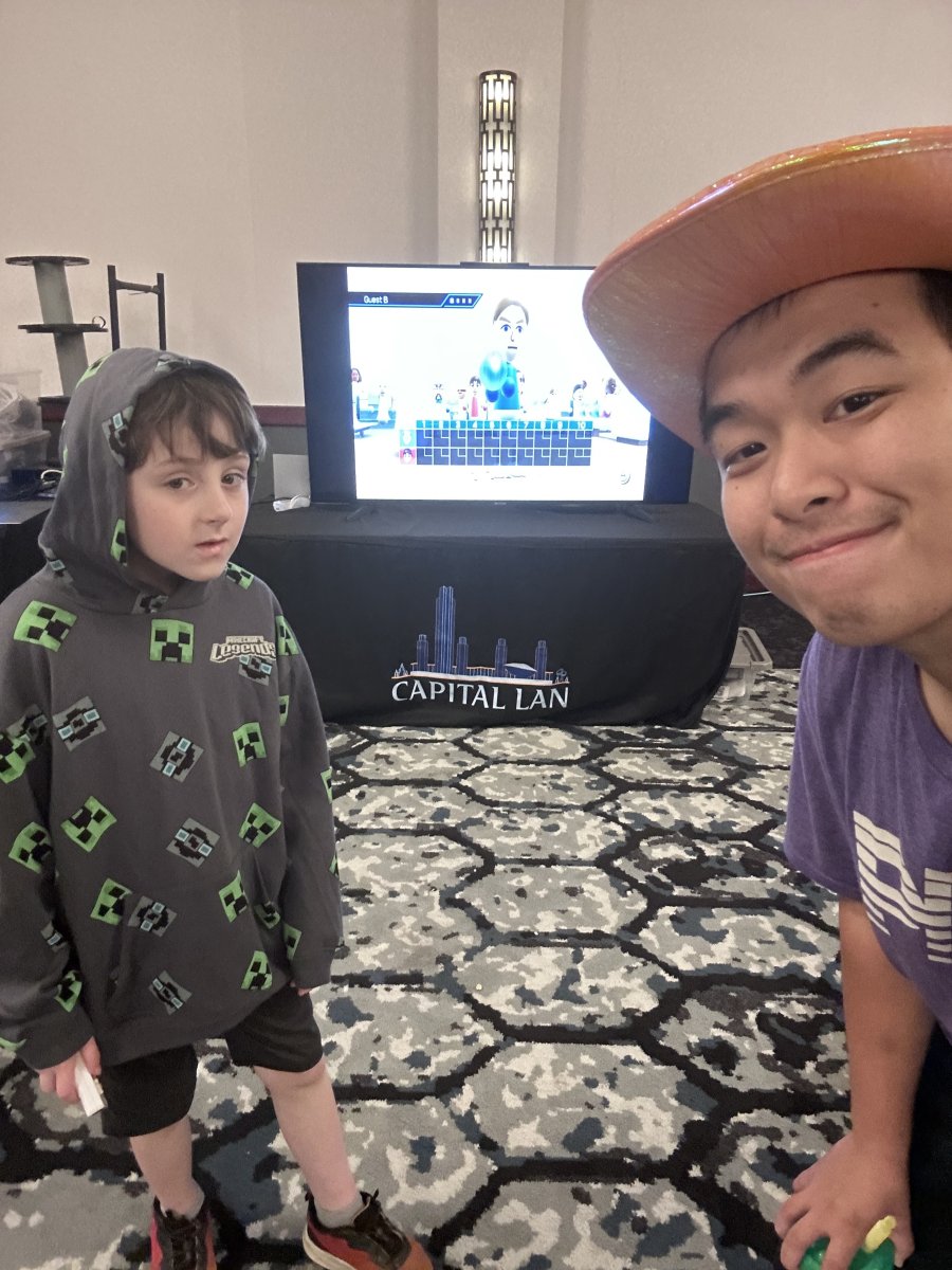 Two attendees posing near a Wii Sports game setup