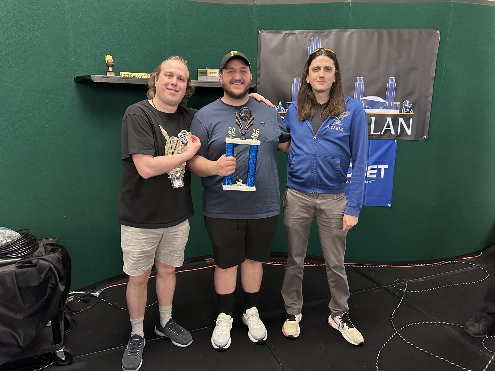 Three attendees posing with a trophy