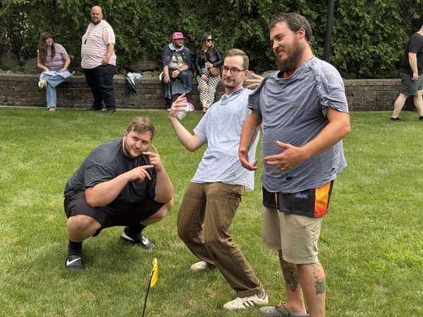 Three attendees posing on grass outdoors