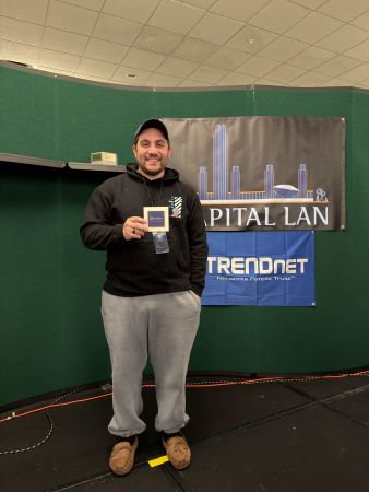 Attendee posing with badge at sponsor banners