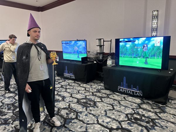 Attendee in wizard costume holding trophy near Wii Sports Go
