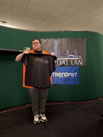 Person holding a Capital LAN t-shirt on stage
