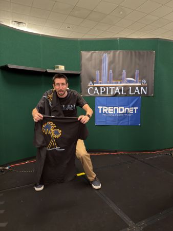 Person holding Capital LAN T-shirts on stage