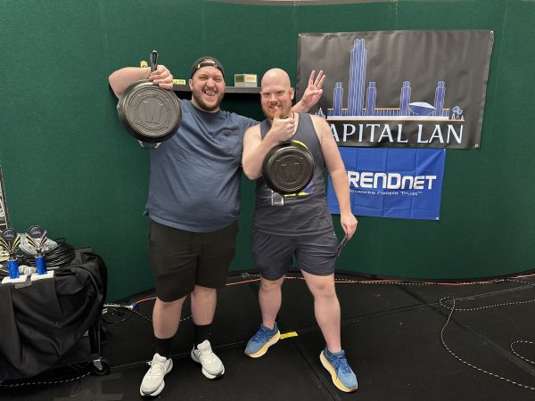 Two attendees holding frying pan prizes