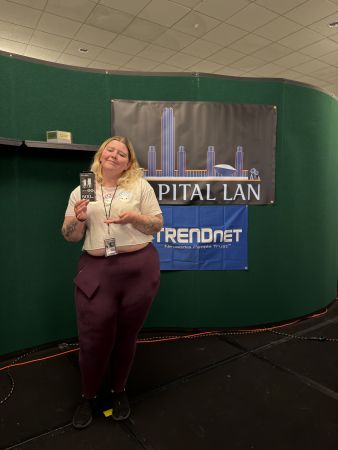 Attendee holding prize in front of event banners