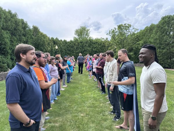 Two lines of attendees facing each other outdoors