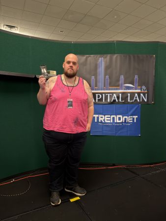 Attendee holding prize in front of Capital LAN banner