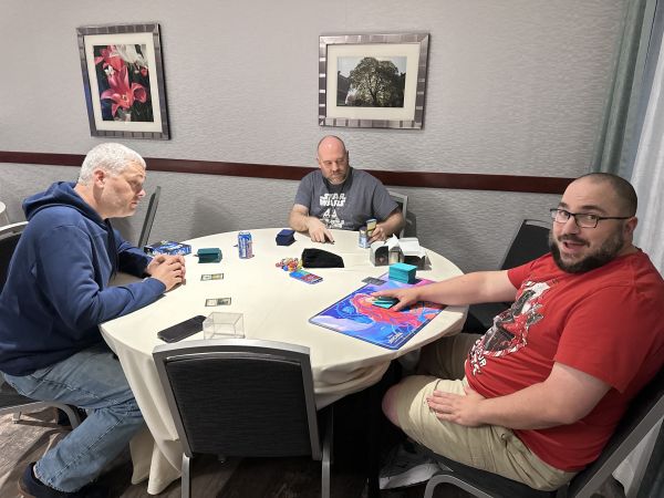 Three attendees playing a card game at a round table