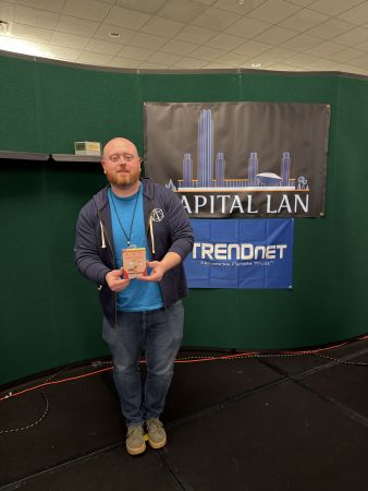 Attendee holding prize in front of Capital LAN banner