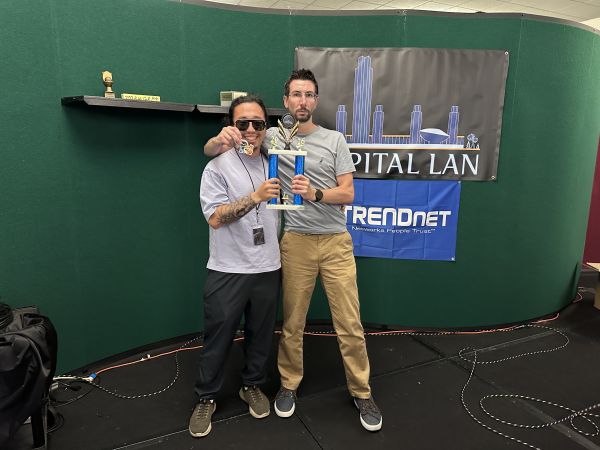 Two attendees holding a trophy and medal